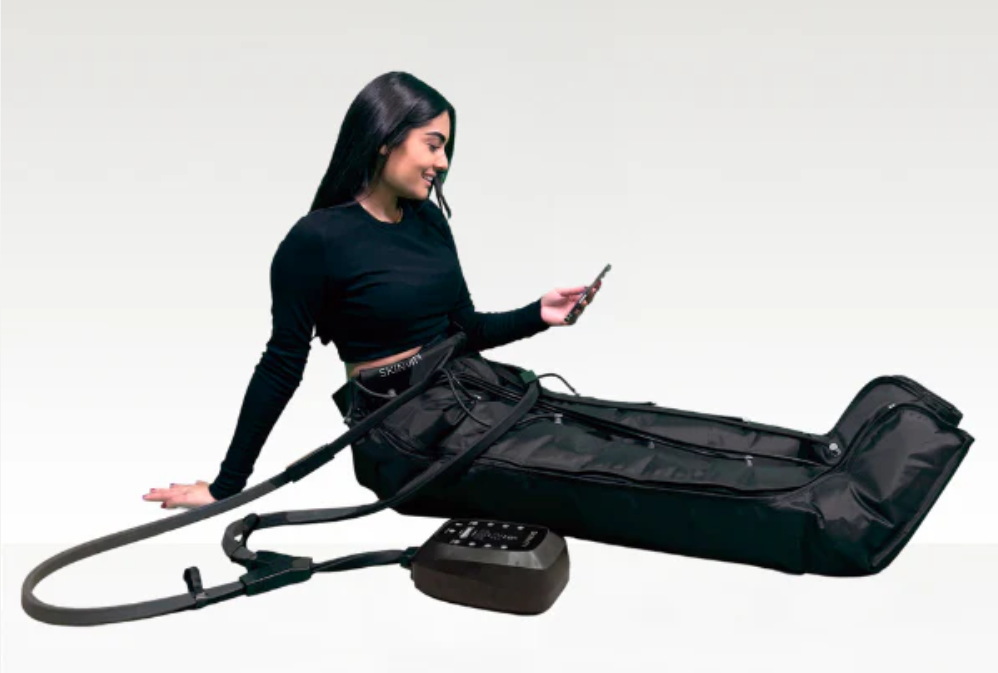 Mujer relajada usando el dispositivo PressTech de Skinvity en casa para aliviar piernas cansadas y reducir celulitis
